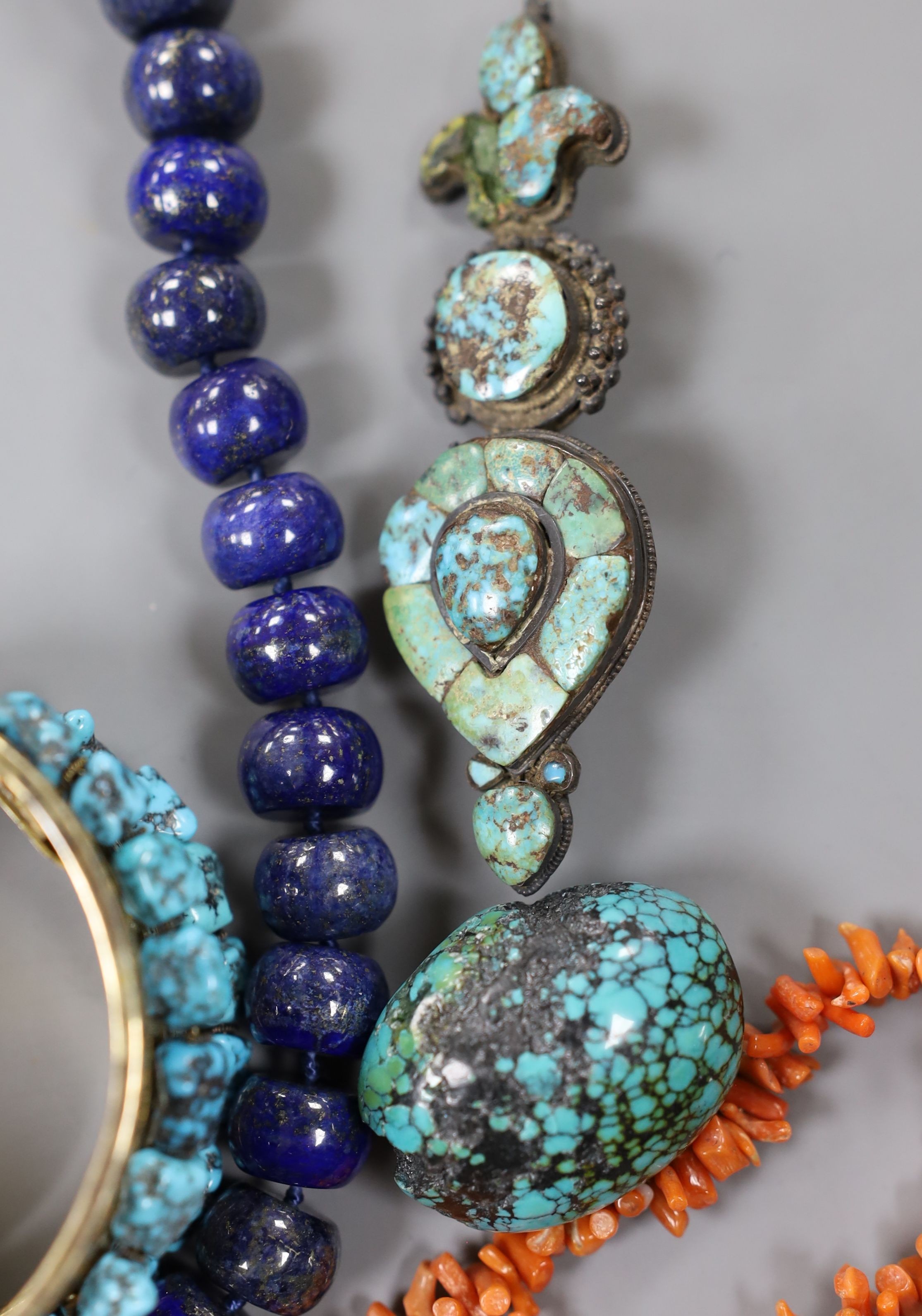 A lapis lazuli necklace, 48cm, a coral necklace and a group of turquoise set jewellery, including a gilt white metal two row hinged bangle and an antique pendant?.